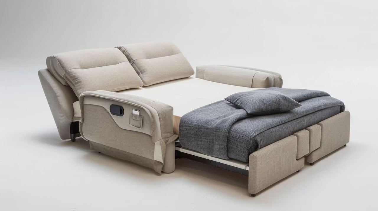 Sofa bed extended into a bed with a beige base and gray blanket.
