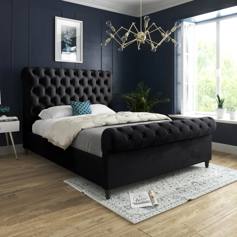 Stylish bedroom with a king-size bed featuring a dark tufted headboard, modern chandelier, and large window.