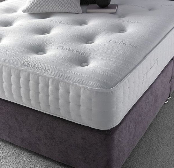 A luxurious white quilted Double Bed Mattress Size UK labeled "Cashmere" on a dark grey bed frame.