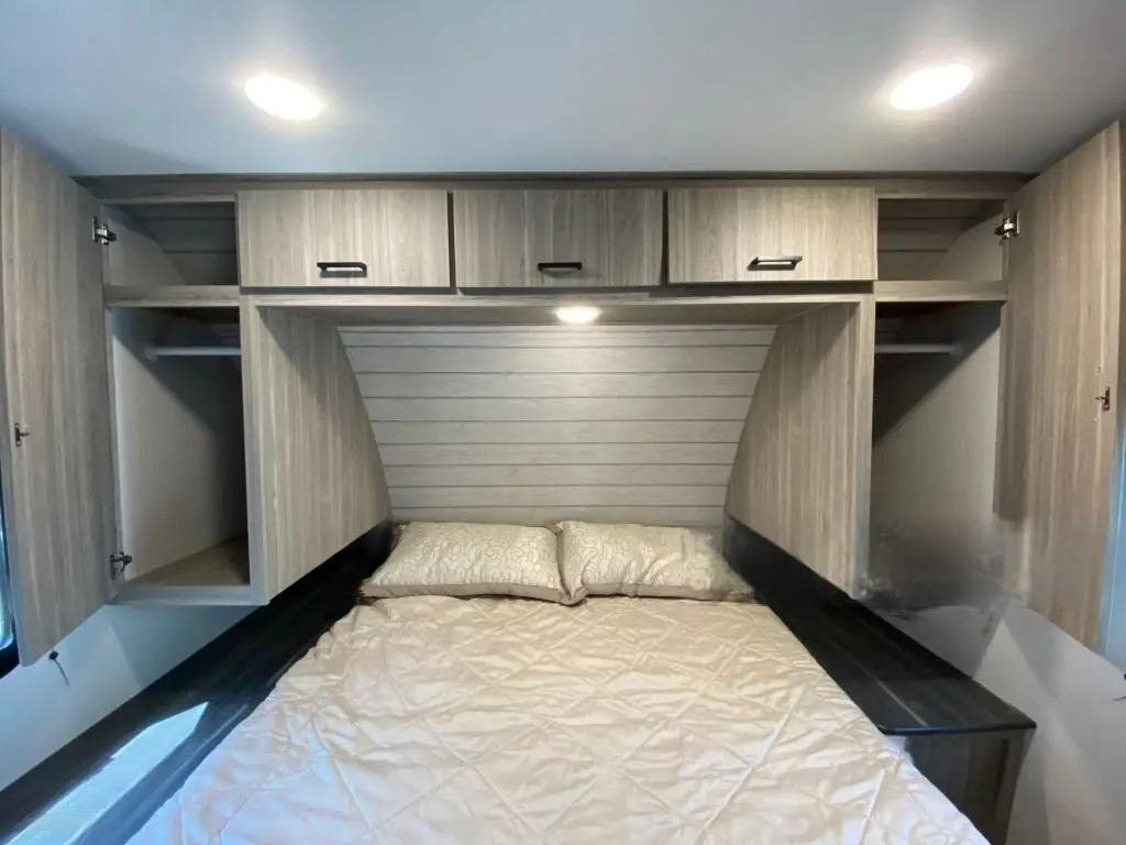 Bedroom with a bed, light wood cabinetry for overbed storage, and ceiling lights.