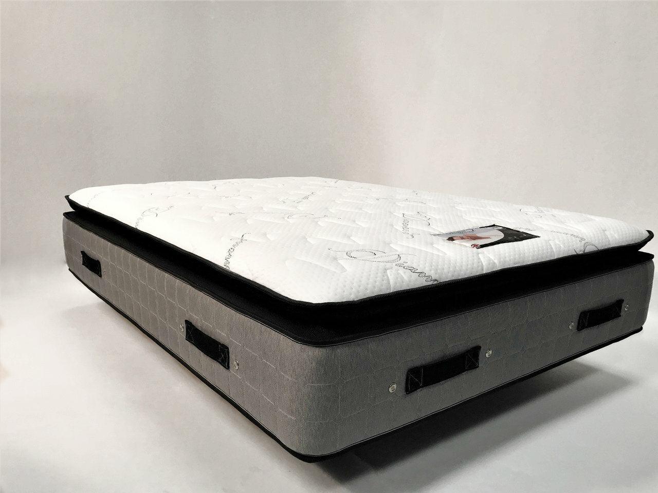 A light gray luxury mattress with a quilted white top and black handles on its sides.