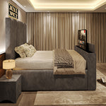 A stylish grey upholstered 2025 Belgravia TV Bed with a tall headboard, integrated TV, and bedside table in a modern bedroom.