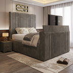 A sophisticated grey 2025 Belgravia TV Bed with a tall, fluted headboard and footboard, featuring a hidden TV in a modern bedroom.