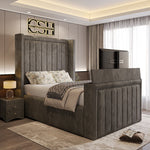 
A modern grey 2025 The Astoria TV Bed with a tall, panelled headboard and a pop-up TV footboard, enhancing a stylish bedroom.