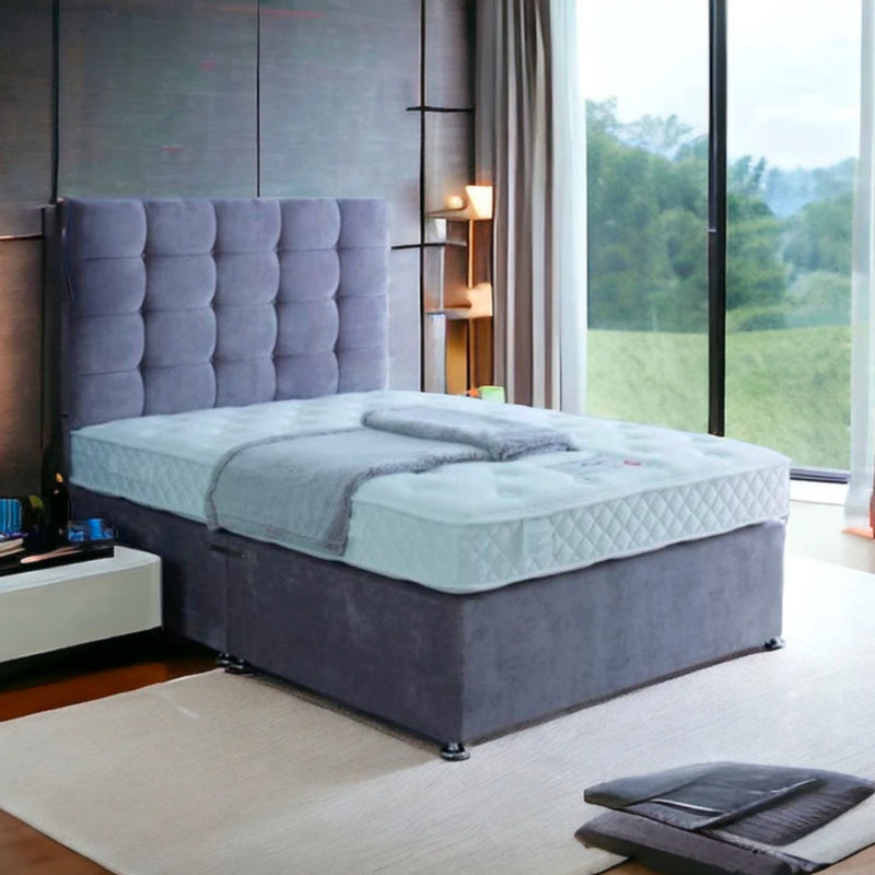 A modern bedroom with a grayish-blue bed and tufted headboard, labeled Excellence 1000.