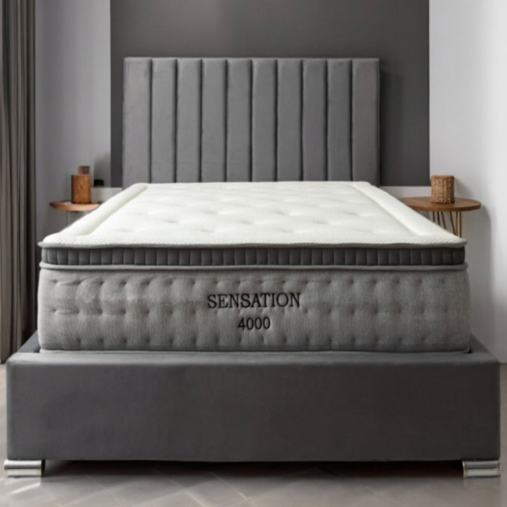 Bedroom with a large bed featuring a "Sensation 4000" mattress with a grey padded headboard. Main image